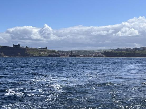 View from a boat into Whitby harbour. On left hill ruins lighthouse in centre