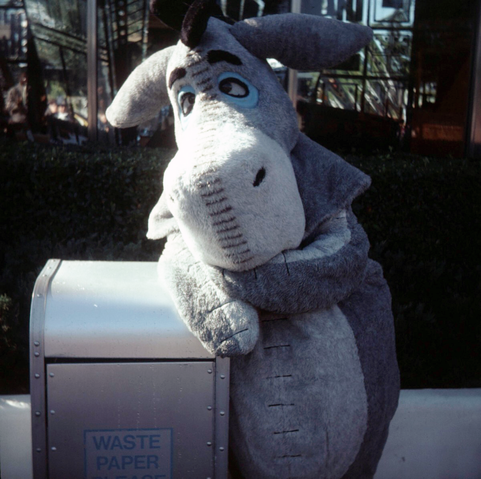 Eeyore, the classic Winnie the Pooh character, leans despondently against a 'WASTE PAPER' trash can in Tomorrowland at Magic Kingdom, Walt Disney World, circa 1978.