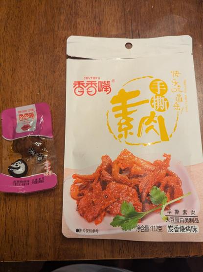 Joytofu brand spicy tofu snack. Big white packet with a small packet next to it with a portion of the red chili oil covered tiny tofu nuggets