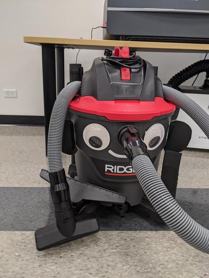 Photograph of a shop vac with googly eyes and cartoon smile