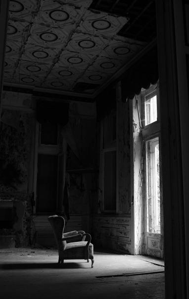 dark black and white image of a a chair in an empty room in front of a window

Stock image? artist unknown.