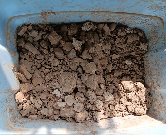 Crumbled clay in bottom of blue snap-lid tub.