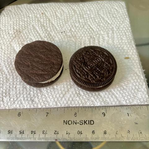 Two Oreo MEGA Stuff (yes they have those) cookies side by side, identical except that one is missing the classic Oreo stamp on the cookie, having been affixed to the sandwich upside down. 