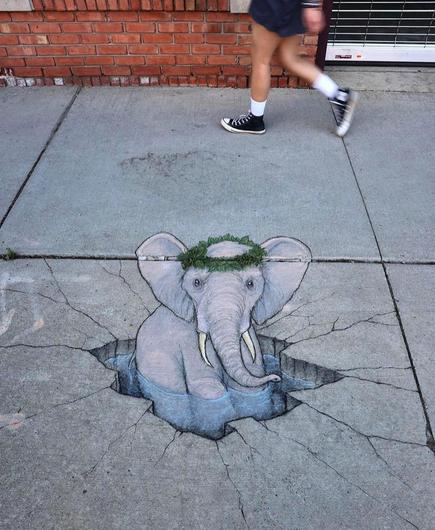Streetart. An elephant (named Maureen) and a water hole with a 3D effect were drawn with chalk on the ground of a sidewalk with some green weeds in the cracks. The ring of green weeds has been integrated into the drawing as a decorative hairband for the elephant. A stressed gray elephant with two pretty tusks and a headband now looks out of a hole filled with water, while a real passer-by walks by in the background. Title: 
