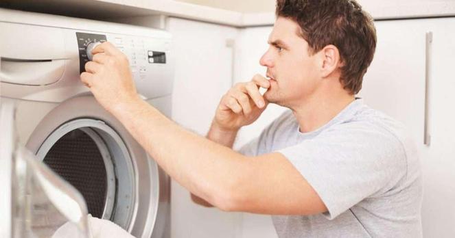 Man looking at washing machine settings