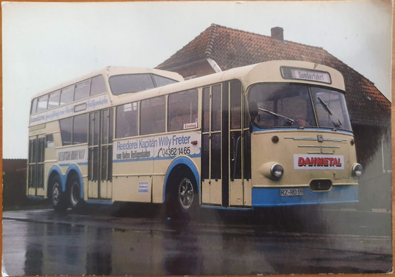 An old creme-colored German bus, the second half at the back is a double decker! 