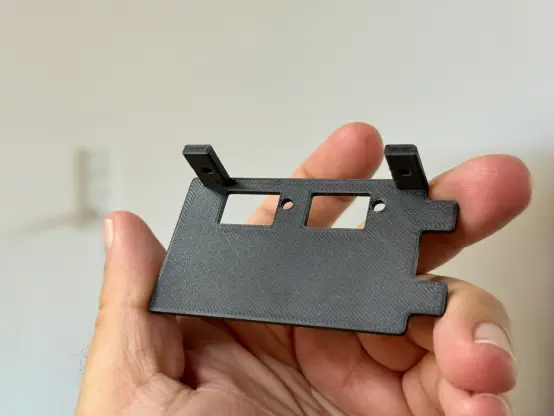 A hand holding up a 3D printed bracket