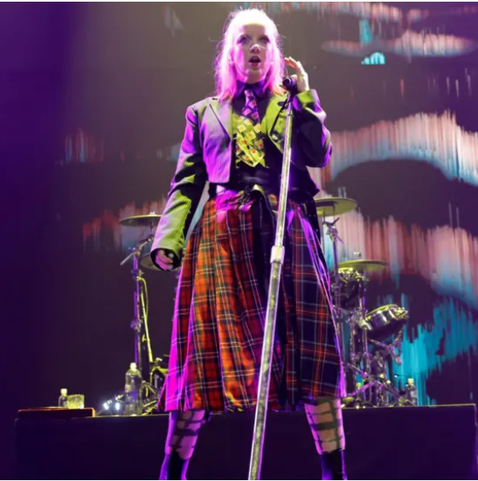 Picture of singer Shirley Manson at the microphone on stage with Garbage. She is dressed in a red tartan kilt, an indication of her Scots identity