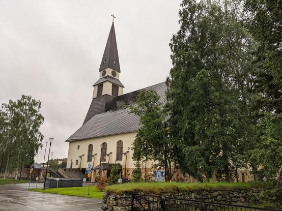 L'église de Rovaniemi, encadrée par des arbres. Le ciel est gris, il pleut.