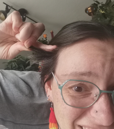 A brown haired (silver graced), white millenial woman with rainbow earings and a look of despair on her face (the woman being me), holding out 4 cm long hair strands that stick out of my head and make me look ridiculous. 

I am looking for someone who can give me advice or point me to a turorial of how to praid this hair strainds to my scalp until they are long enough to go into my normal pony tail. 
I even consider going to an african hair salon if someone says, that it is possible to braid this short of lengh in a way, that will stay braided for a week or so and they will be able to handle this ( idk if i am able to do it with my clumbsy ass fingers)
