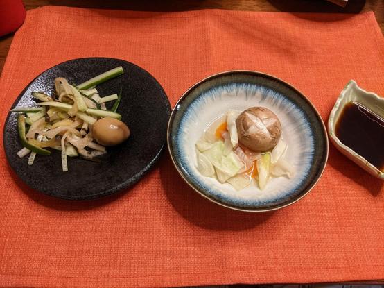 Small bowl with vegetables and a mushroom and a small plate with daikon+ cucumber julienne salad and a soy marinated quail egg. 
A small dish with a dark ponzu is also on the table mat