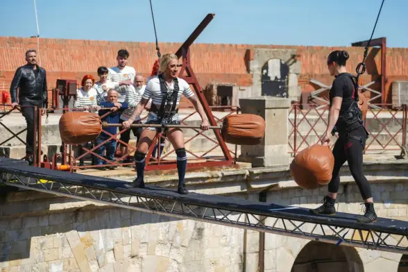 Lolita Banana, drag queen and contestant on Fort Boyard, faces Lady Boo, in an aerial cotton buds battle. The battle takes place on top of a narrow beam suspended above the courtyard of Fort Boyard. Both Lolita Banana and Lady Boo hold a giant cotton bud that weighs 8kg. The cotton bud is used both for balance and for knocking the opponent off the beam. Both competitors are wearing a safety harness attached to an elastic cord.

Lolita Banana's teammates, as well as the host Olivier Minne, look on.