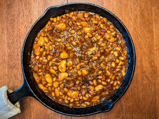 Top view of a cast iron skillet filled with BBQ beans (including navy beans and large butter beans)