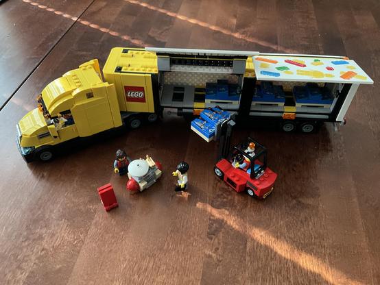 Photo of the completed truck, with a forklift loading a pallet of Lego boxes into the trailer, with a small hot dog stand on the side.