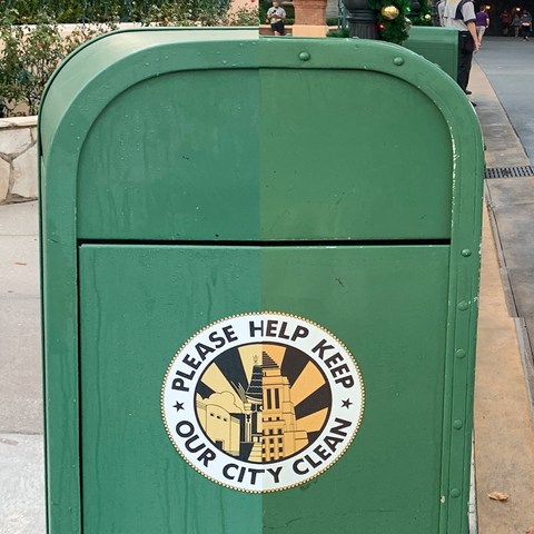 A green trash can split down the middle with a circular label that reads 