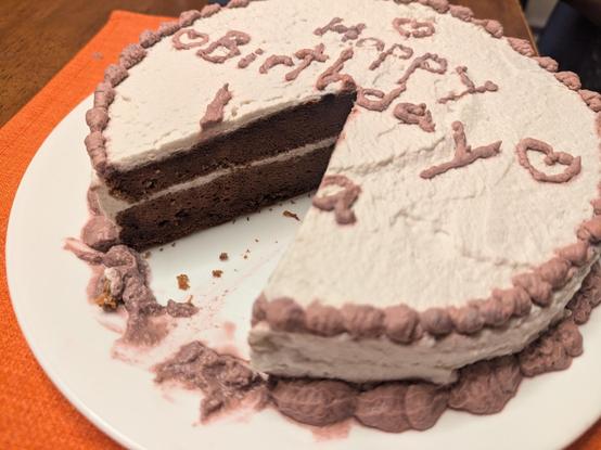 Cake with white frosting and a cut wedge showing the inside of chocolate