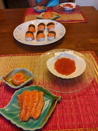 Salmon nigiri (gunkan) and sashimi and ikura in plates on a table - servings for 2 kids