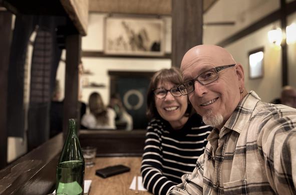 A smiling man and woman taking a selfie at a table in a cozy restaurant.