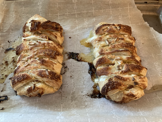 Two pizza braids on a sheet of parchment paper just out of the oven 