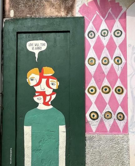 Streetartwall. On an old green wooden door next to a pink patterned wall, an artist has painted a beautiful mural with a figure as an illustration to the song title 