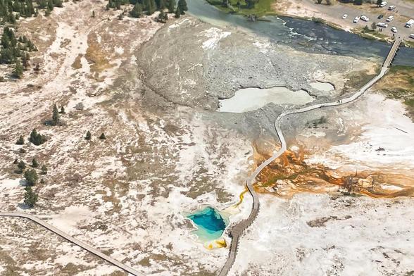 This image shows the area where a hydrothermal explosion occurred on July 23, 2024 in Yellowstone's Biscuit Basin.

The light gray area in the upper middle part of the photo shows how far fragments of rock and mud were tossed during the explosion. While the location is near the boardwalk and visitors were present, no injuries were reported.

Hydrothermal explosions are violent and dramatic events. With little to no warning, boiling water, steam, mud, and rock fragments are hurled into the air. These are not volcanic eruptions, but rather sudden episodes of water flashing to steam underground. They are the most frequently occurring hazard in Yellowstone.

Small hydrothermal explosions like this happen almost annually in the Park. Every few thousand years, large ones can also occur. The park is home to the largest-known hydrothermal explosion crater on Earth—Mary Bay, on the north side of Yellowstone Lake, which is 1.5 miles across.

Based on this aerial shot, it’s easier to see why nobody got hurt.
It belched across a short section of the boardwalk, instead of belching the opposite direction(the longer length of the boardwalk). Still a miracle that nobody got hit by debris or burned by the steam explosion though.

Photo take July 23, 2024 by NPS / Joe Bueter.