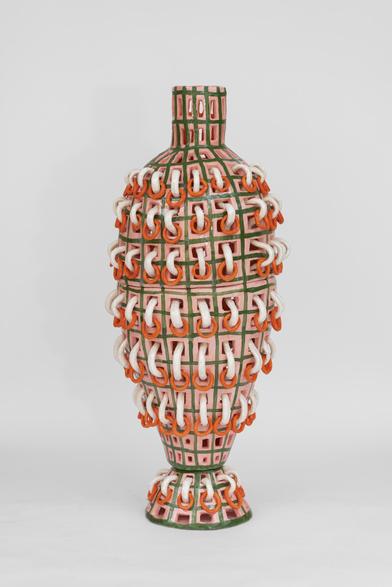 Abstract ceramic sculpture in an oblong vase shape, covered in a green and pink grid pattern with white and orange rings erupting in horizontal rows