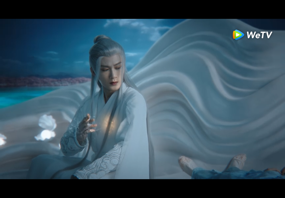 Xiang Liu sitting in a white sea shell, looking at Xiao Yao who is unconscious. He is activating the poisonous love bug.