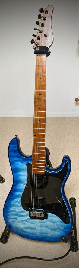 A guitar with a watery blue body and dark wood neck. It's s stratocaster from the company 
Schecter.