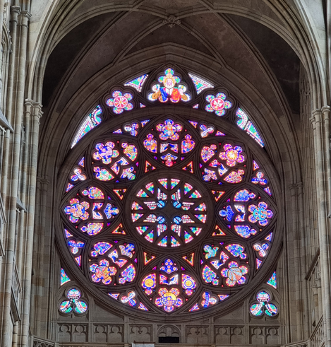 A gothic-style window with a plenitude of colored inlays in circular patterns around the center.