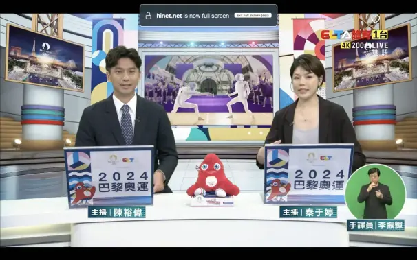 Screen capture of ELTA TV, the official Taiwanese broadcaster of the Paris 2024 Summer Olympic Games, with two speaking commentators behind the anchor desk, as well as a sign language commentator at the corner.
