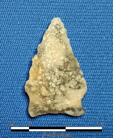 White to gray translucent stone. Small triangular blade point with indented side hafting & concave base. It is 2.75 cm long & 1.75 cm wide.