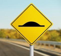 A yellow speed bump sign