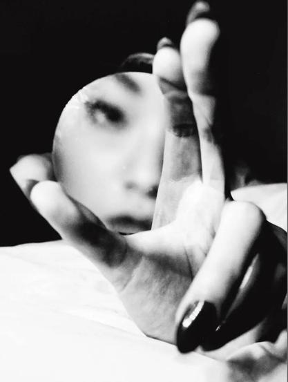 Photography. A black and white photo of a woman's face in the mirror. A hand with painted fingernails can be seen in the foreground. She is leaning on a white background and her fingers are spread out as if she is trying to grasp something. Between the fingers is a round mirror in which the face of a young Asian woman can be seen. A confusingly beautiful portrait.
Info: Jack Davison is one of Britain's leading portrait photographers, but that is too simple a description, as his love of experimentation is multi-layered. He started out looking for inspiration in Flickr images and the photos of famous photographers and remixed everything. He finds the surreal in the everyday, his mysterious images blurring the boundaries between reality and the dream world.