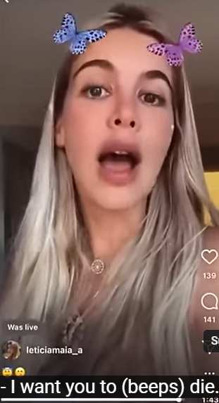 A young blonde woman with evident beauty treatments such as lip injections addresses the camera - the short is of her head and shoulders and is in portrait mode. There is a butterfly filter on the shot as she speaks so she has a pink and a blue butterfly positioned at either side of the top of her forehead. 
The subtitles translate her Brazilian Portuguese speech as 
