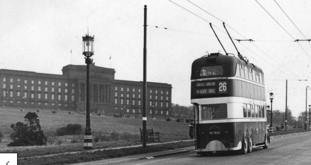 In the background on a hill stand Stormont Parliament buildings painted in black pitch as a camouflage measure during the Second World War. A trolley bus passes by in the foreground
(Belfast Telegraph collection, NMNI)