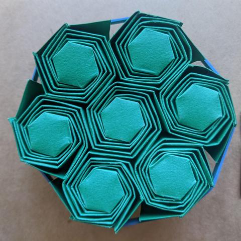 Photograph of seven spiral-wrapped origami hexagons, packed closely together
