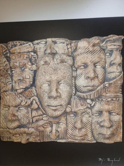 A sculpted wall hanging of many faces crammed together or even merged with a texture reminiscent of Egyptian archaeological digs.