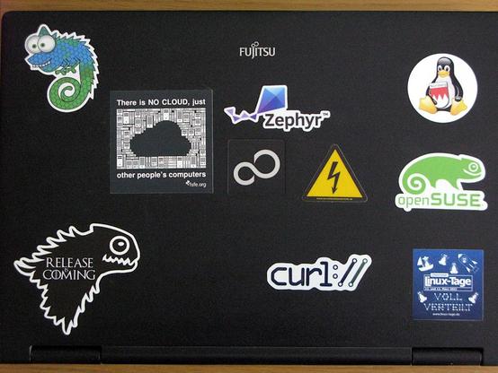 Ein Notebook Deckel mit verschiedenen Aufklebern, von Zephyr, curl, openSUSE, fsfe.org, Chemnitzer Linuxtage und rechts oben unser neuer Franken-Tux. 