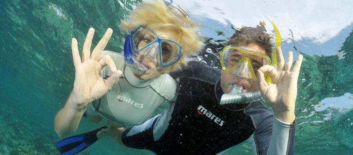 Sous l'eau, deux personnes portant masques de plongée et tubas font le signe convenu pour 