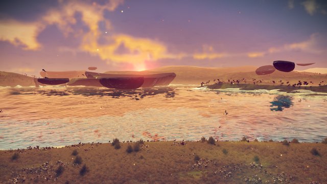 An alien world in the video game No Man's Sky. facing east, there's some water and the plateaus on the far shore are reflected in the water. The sun is starting to rise, and there are wisps of clouds against a lavender sky that you can still see stars through.