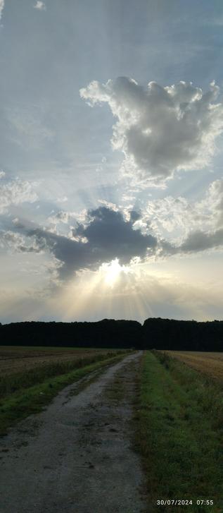 Soleil caché en partie d'un voile nuageux ce qui provoque un effet de rayons lumineux 