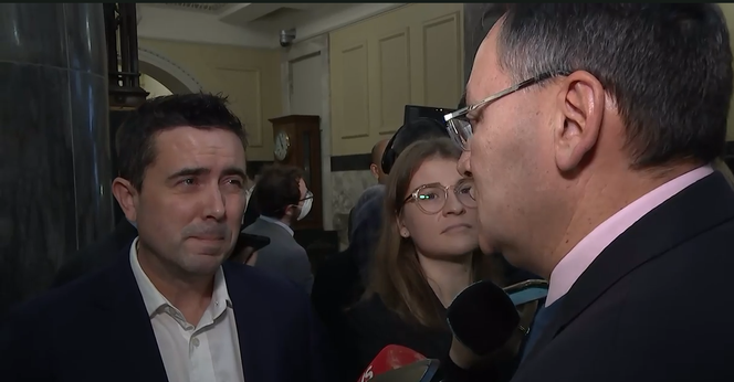screenshot of a TVNZ reporter interviewing New Zealand's Minister of Health Doctor Shane Reti at Parliament