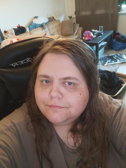 fat trans girl with long messy hair and blue eyes smiling slightly at the camera