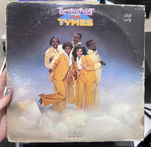 Album cover showing three Black men and two Black women, all smiling and wearing matching mustard-colored suits, posing close together on a foggy sound stage 