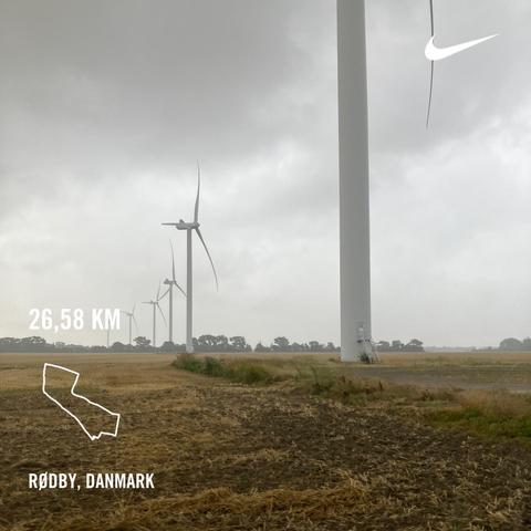 Windmills in a field. The weather i gloomy. There is a graphics overlay with informtion about my run.