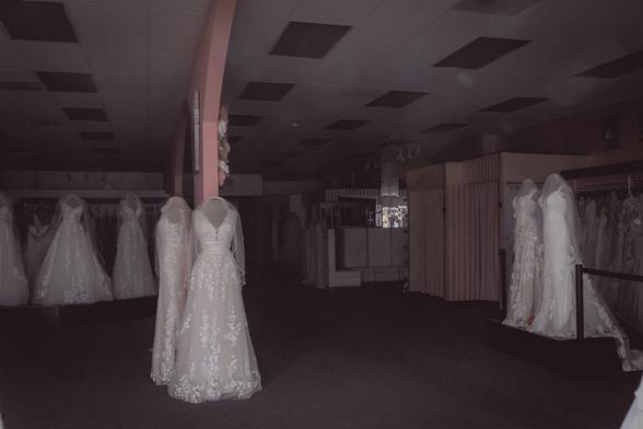 photo of a dark room with bridal gowns on forms scattered around