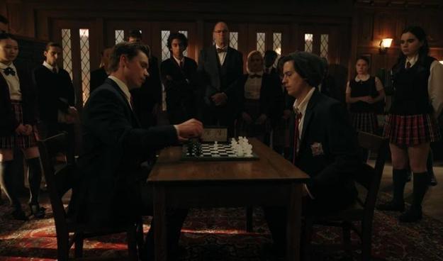 In a season 4 episode of Riverdale, Cole Sprouse as Jughead plays chess in a wood-paneled room at a fancy prep school.