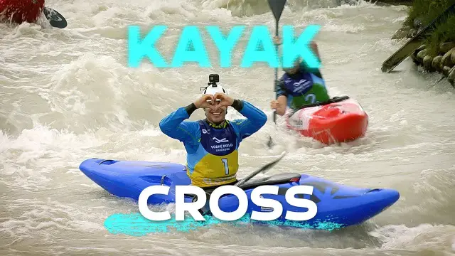 Kayakers competing in whitewater rapids in Kayak Cross. The kayaker in front is posing to the camera forming a heart shape with his two hands.