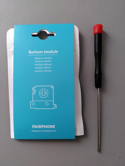 Foto de un paquetito con el módulo inferior de un Fairphone 3 junto con un destornillador.