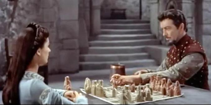 In a scene from Knights of the Round Table, Robert Taylor and Maureen Swanson play chess in a castle.